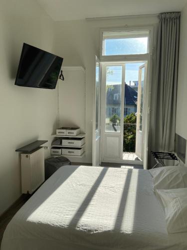 a white bedroom with a bed and a window at Le Relais de l'Orangerie in Strasbourg