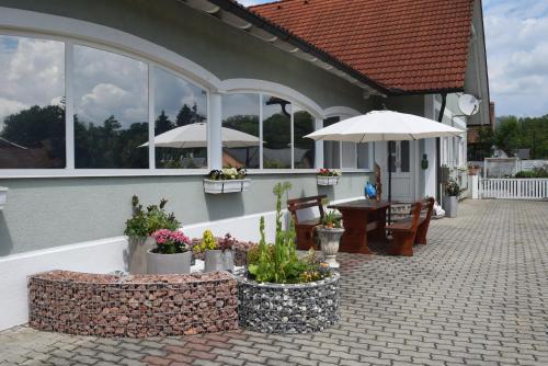 une terrasse avec une table, des chaises et des parasols dans l'établissement Gästehaus Sabina- Frühstückspension, Bed & Breakfest, à Bad Radkersburg