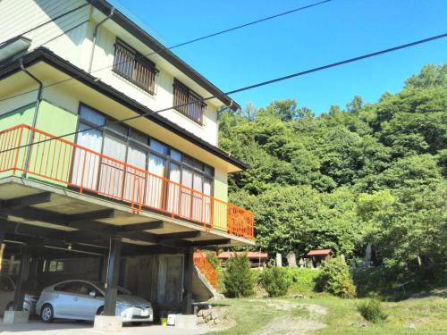 a house with a balcony and a car parked outside at Guest House Hostel yukuru in Iiyama
