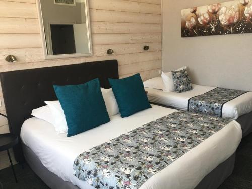 a hotel room with two beds with blue pillows at La Bonbonniere - Sure Hotel Collection by Best Western in Talant
