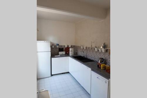 une cuisine avec des armoires blanches et un réfrigérateur blanc dans l'établissement Jardin de Curé, à Cluny