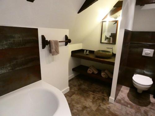 a bathroom with a tub and a toilet and a sink at Auberge du Lac in Mandailles