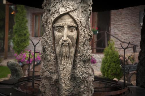 una estatua de un hombre asomándose por detrás de un árbol en Stara Pravda Villas, en Bukovel