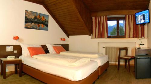 two beds in a room with a tv in a room at Hotel Bologna in Brunico