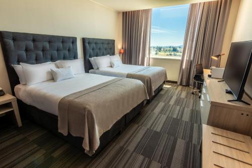 um quarto de hotel com duas camas e uma televisão de ecrã plano em MDS Hotel Chillan em Chillán