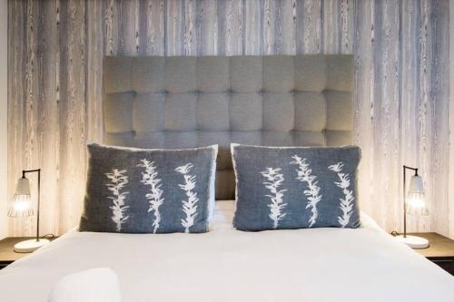 a bedroom with a bed with two blue pillows at Waters Edge Apartments in Cape Town