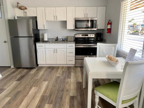 a kitchen with white cabinets and a table and a refrigerator at Ocean Eleven Suites in New Smyrna Beach