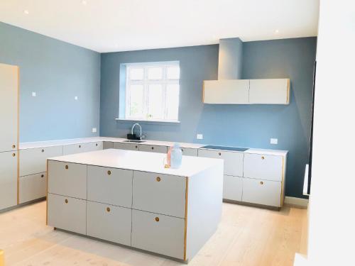 una cocina con armarios blancos y una pared azul en aday - 4 Bedroom - Modern Living Apartment - Aalborg en Aalborg