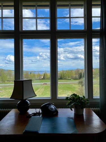 a desk with a lamp and a window with a view at Bergsgården Hotell & Konferens in Bergsgården