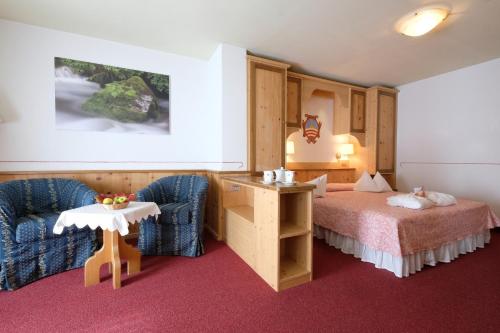 a hotel room with a bed and two chairs at La Roccia Wellness Hotel in Cavalese