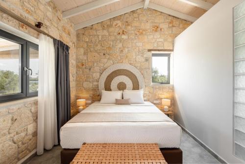 a bedroom with a large bed and a stone wall at "Four Olives" Luxury Rooms, Afitos #FeelsLikeHome in Afitos