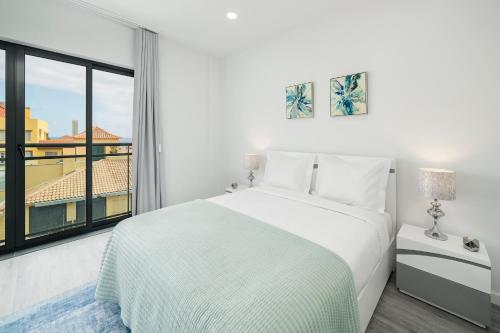 a white bedroom with a bed and a large window at Santa Luzia by An Island Apart in Funchal