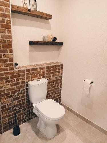 a bathroom with a white toilet and a brick wall at Apartment Dubnica Prejta 3 in Dubnica nad Váhom