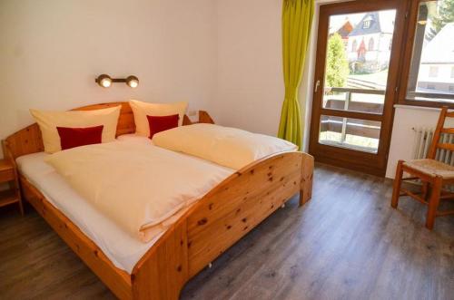 a large wooden bed in a bedroom with a window at Schwarzwaldmädel-Ferienwohnungen in Todtnau