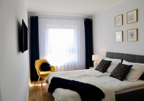 a bedroom with a bed with a window and a yellow chair at Apartament Gdańsk Baltica Towers 7floor in Gdańsk