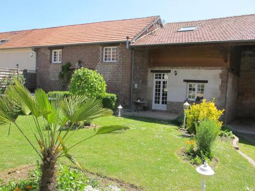 a brick house with a yard with plants at Gîte Cosy Green in Chevincourt