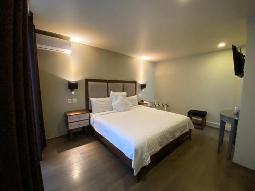 Un dormitorio con una gran cama blanca y una mesa en Suites Lerma 205, en Ciudad de México