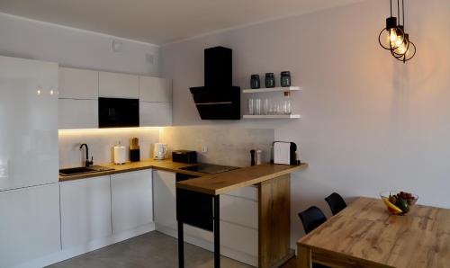 a kitchen with white cabinets and a wooden table at Apartament Gdańsk Baltica Towers 7floor in Gdańsk