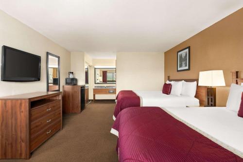 a hotel room with two beds and a flat screen tv at Baymont by Wyndham Cortez in Cortez