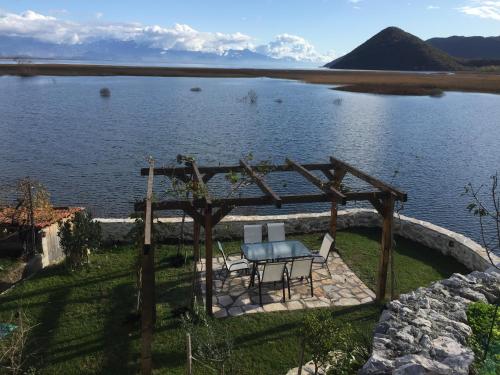 a table and chairs under a pergola next to a lake at Accommodation "MONTELAGO"- Virpazar,Skadar Lake in Virpazar