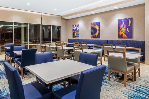 a dining room with tables and blue chairs at La Quinta Inn & Suites by Wyndham Kansas City Beacon Hill in Kansas City