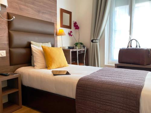 a hotel room with a bed with a suitcase on it at Hôtel Clairefontaine in Paris