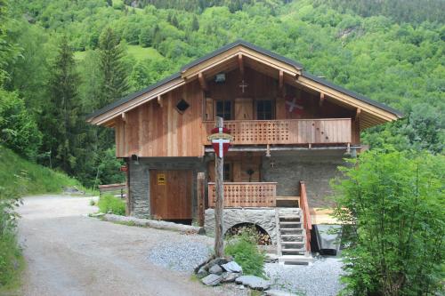 a large wooden cabin with a porch and a driveway at Ferme Saint-Aubin in Sainte-Foy-Tarentaise