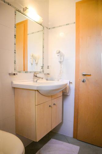 a bathroom with a sink and a mirror and a toilet at Appartements Kirchtalhof in Lana