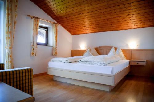 a bedroom with a white bed with a wooden ceiling at Appartements Kirchtalhof in Lana