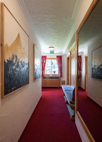 a hallway with red carpet and paintings on the walls at Gästehaus Stotter in Neukirchen am Großvenediger