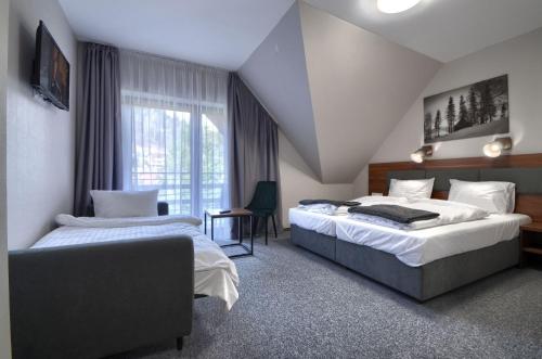 a hotel room with two beds and a window at Gucio - pokoje z restauracją Szczyrk in Szczyrk
