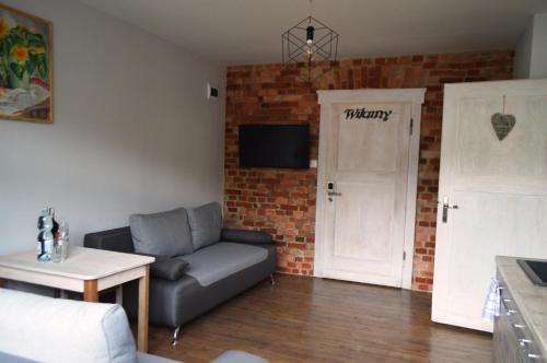 a living room with a couch and a brick wall at Apartament z widokiem na Śnieżkę in Karpacz