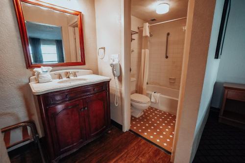 a bathroom with a sink and a toilet and a mirror at Lamplighter Inn and Suites - North in Springfield