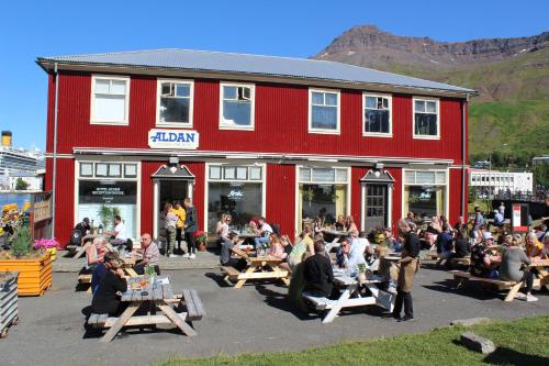 a group of people sitting outside of a red building at Hotel Aldan - The Bank in Seyðisfjörður