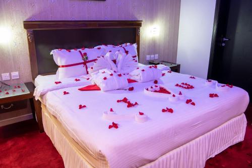 a large white bed with red rose petals on it at Jazan Inn Hotel in Jazan