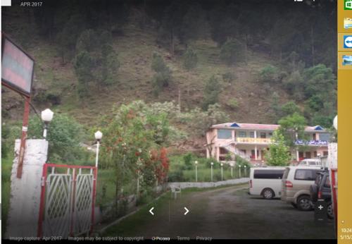 a parking lot with cars parked in front of a mountain at Hotel Royal Park in Hassa