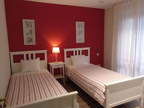 two beds in a room with red walls at Apartamento Turístico Cigüeña de Alfaro in Alfaro