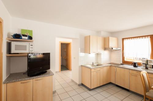 a kitchen with wooden cabinets and a tv in it at Appartements Kirchtalhof in Lana