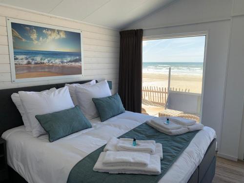 a bedroom with a large bed with towels on it at STRAND 21 hotelchalets in Zandvoort