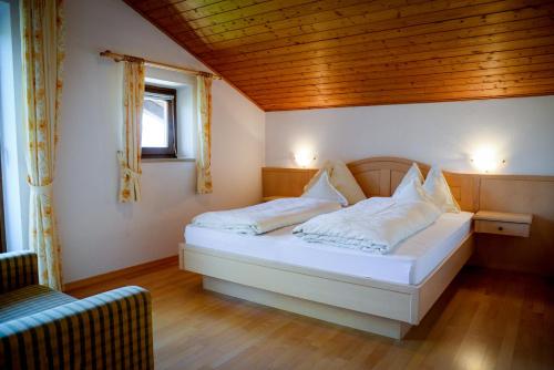 1 dormitorio con 1 cama con sábanas y almohadas blancas en Appartements Kirchtalhof en Lana