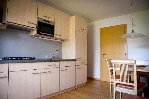 a kitchen with wooden cabinets and a table and a kitchen with a sink at Appartements Kirchtalhof in Lana
