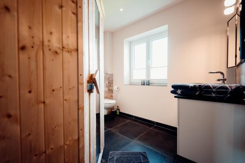 a bathroom with a sink and a toilet and a window at Ferienhaus Loheide - mit Sauna in Langenhorn