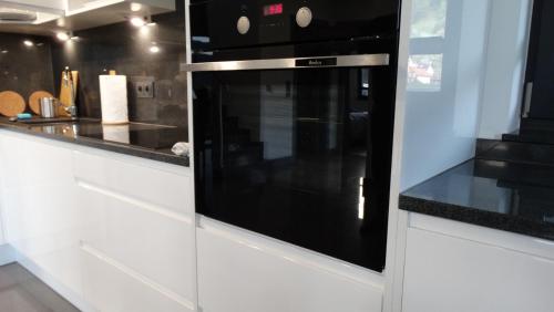 a black microwave oven in a white kitchen at DOMINO-APARTAMENTY Blue in Krościenko