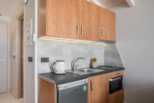 a kitchen with wooden cabinets and a sink at Alektor Luxury Apartments in Zakynthos Town