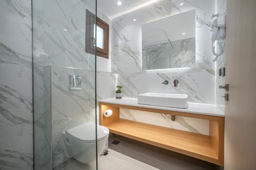 a bathroom with a sink and a toilet and a mirror at Alektor Luxury Apartments in Zakynthos Town