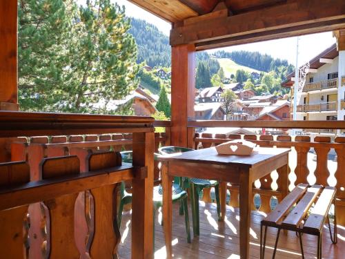 porche de madera con mesa y sillas en el balcón en Appartement L'Ecureuil 8 pers -Prox pistes et centre village-, en Les Carroz d'Araches