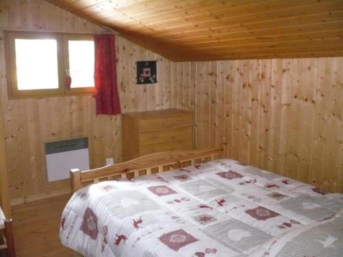 een slaapkamer met een bed in een houten hut bij Appartement L'Ecureuil 8 pers -Prox pistes et centre village- in Les Carroz d'Araches
