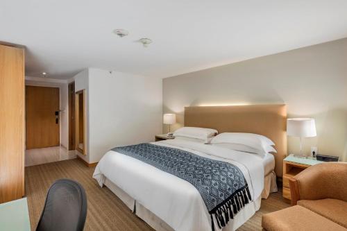 a bedroom with a large white bed and a chair at Presidente InterContinental Puebla by IHG in Puebla