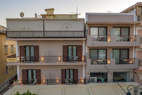 a tall building with balconies and tables on it at Alektor Luxury Apartments in Zakynthos Town
