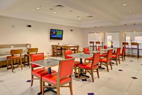 a restaurant with tables and chairs and a flat screen tv at Holiday Inn Express Hotel & Suites Austin NE-Hutto by IHG in Hutto